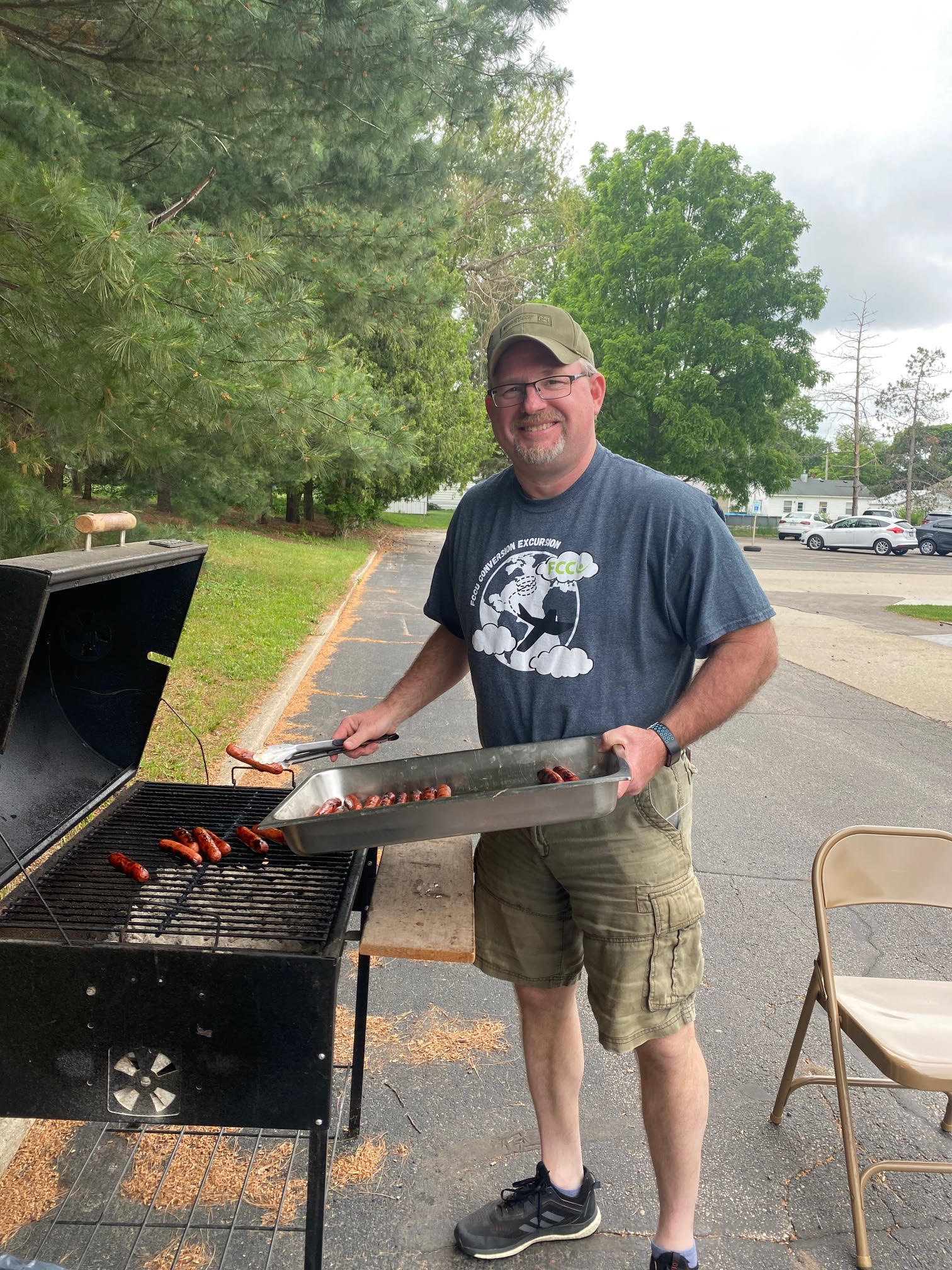 Rob Russell stands next to outdoor grill, grilling brats