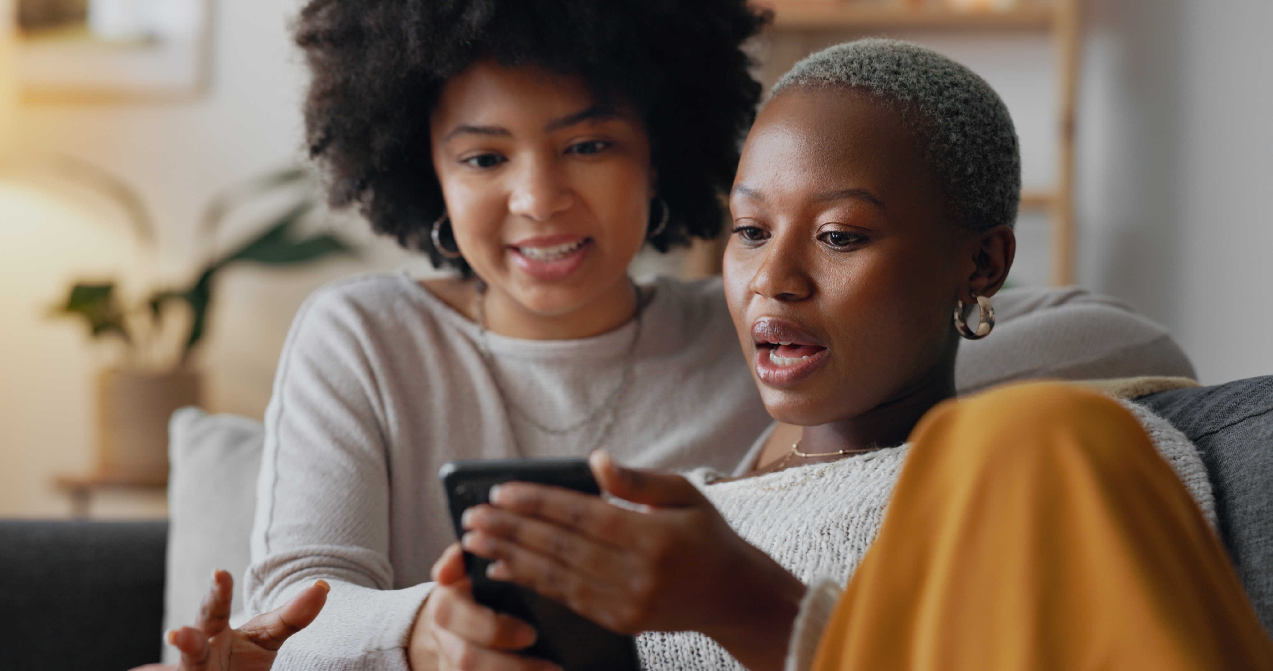 Woman showing her friend something surprising on her smartphone.