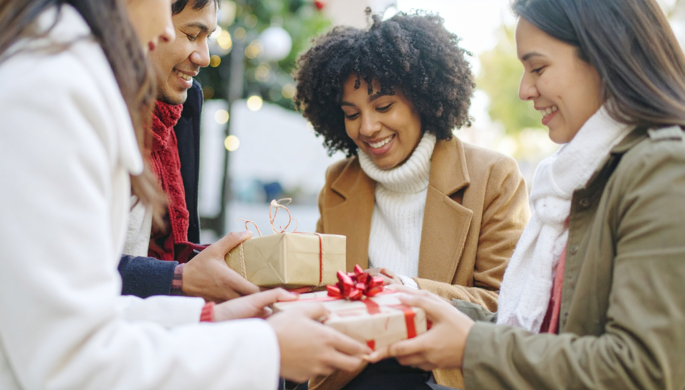 Friends exchanging Christmas gifts outdoors.
