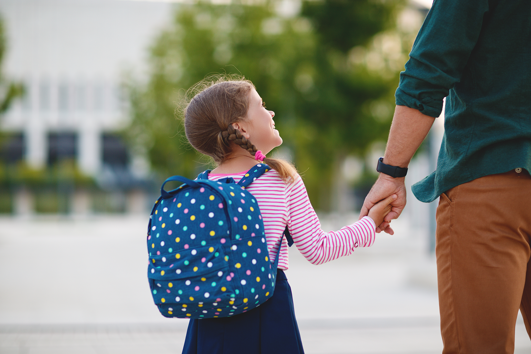 First day at school. father leads a little child school girl in first grade.