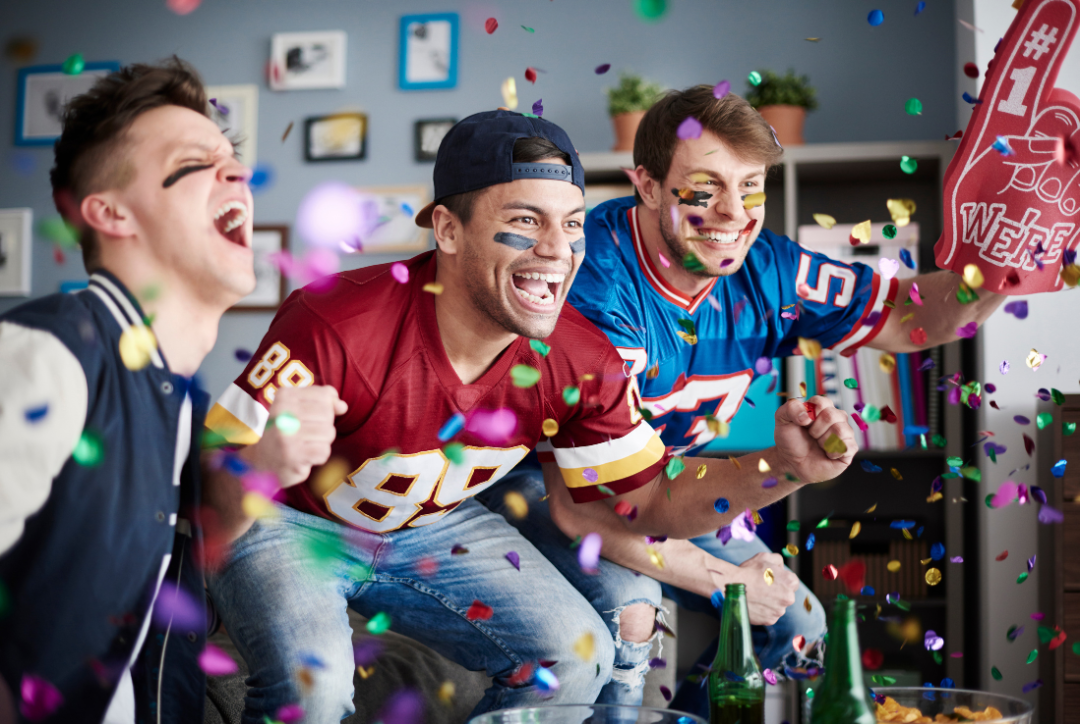 Football fans cheering among falling confetti.